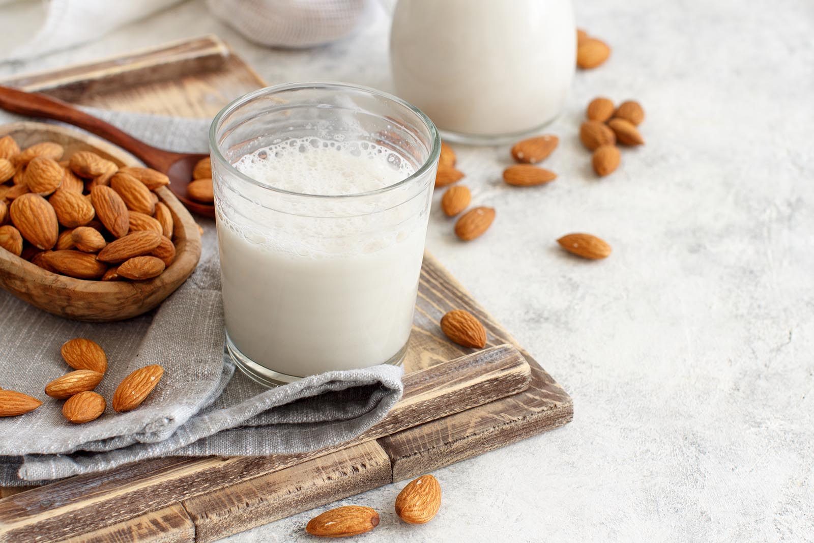 Glass of almondmilk on a tray of almonds