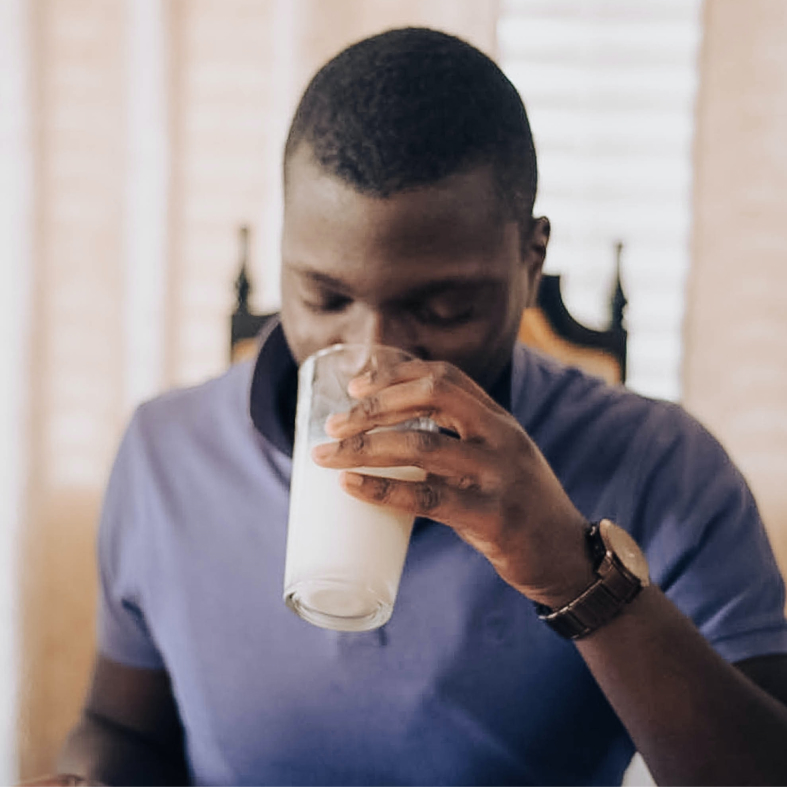 A man drinking a glass of almondmilk