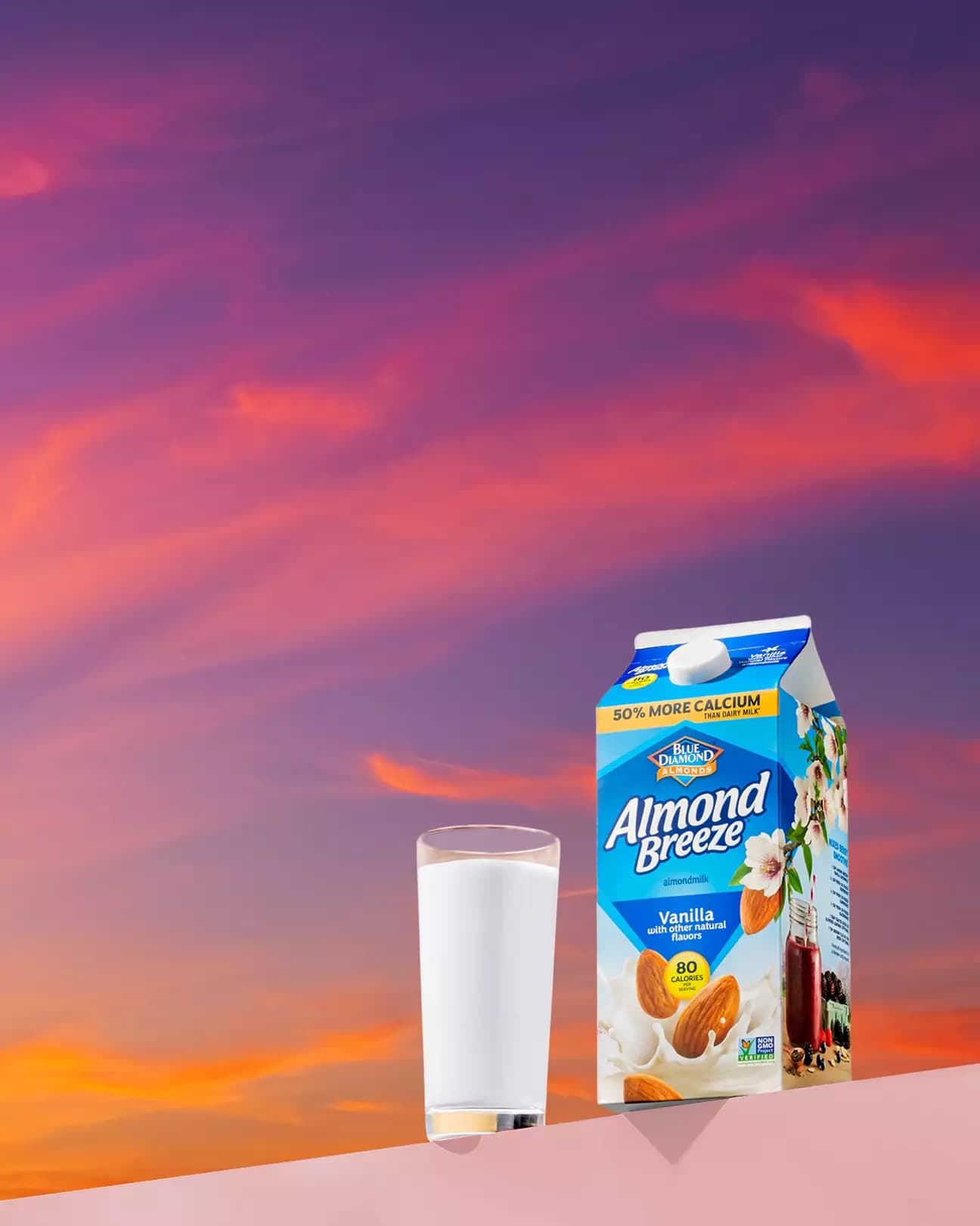 Glass and carton of Almond Breeze almond milk with a sunset background