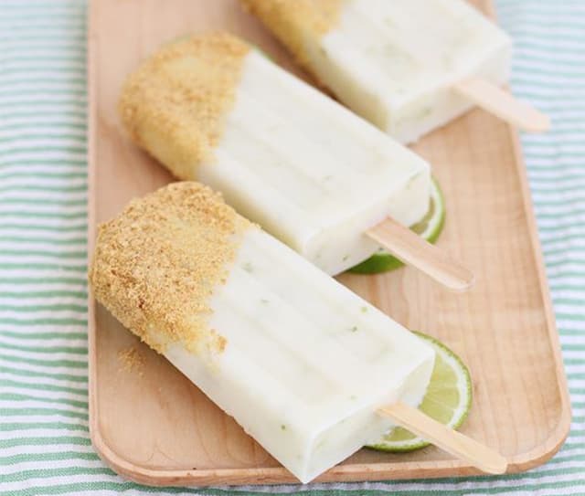 Key lime pie popsicles on a wooden serving platter