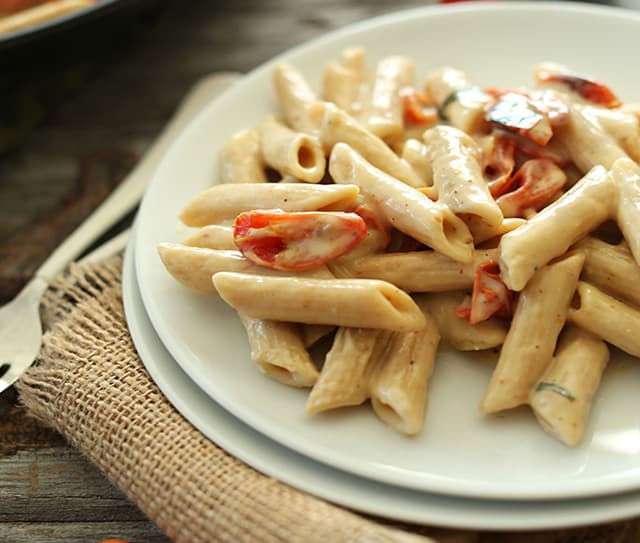 Plate of creamy vegan garlic pasta with roasted tomatoes