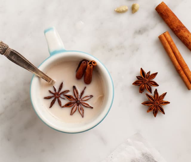 Full mug of almondmilk chai latte garnished with cinnamon sticks