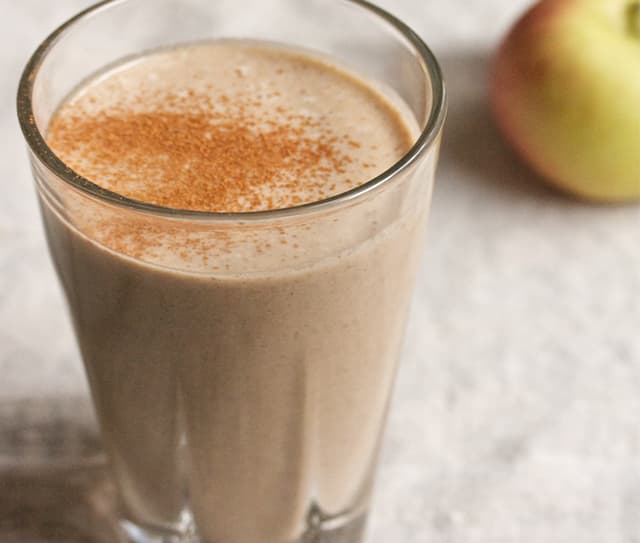Glass full of almond and apple smoothie topped with fresh cinnamon