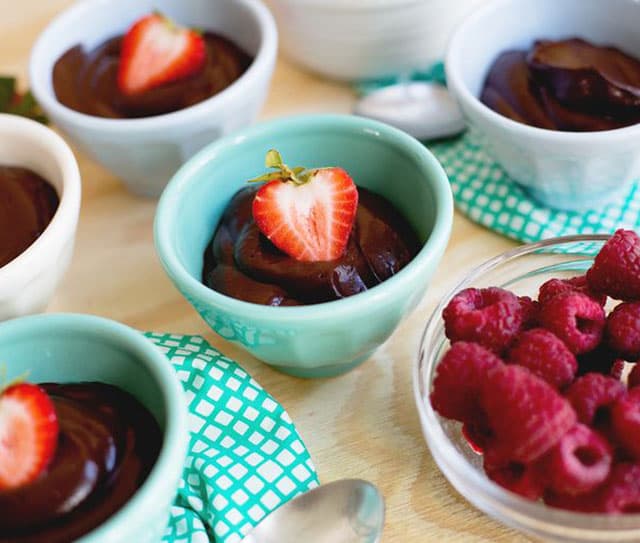 Small bowls full of dairy-free chocolate pudding each topped with a strawberry slice