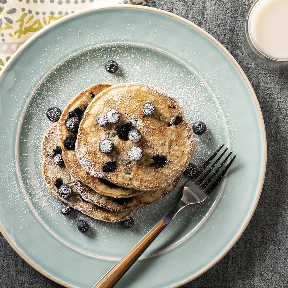 Stack of vegan blueberry pancakes dusted with powdered sugar