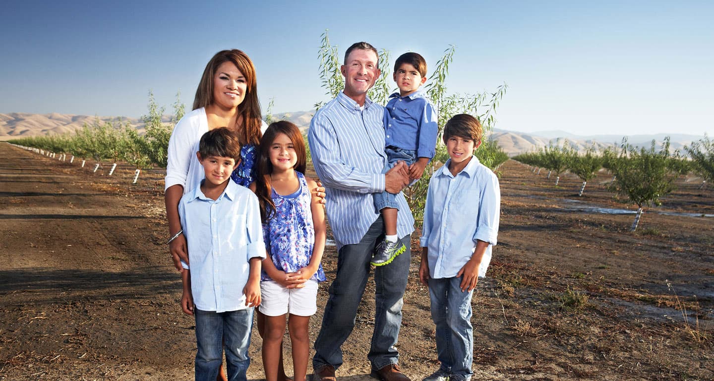 Grower family standing in an almond field.