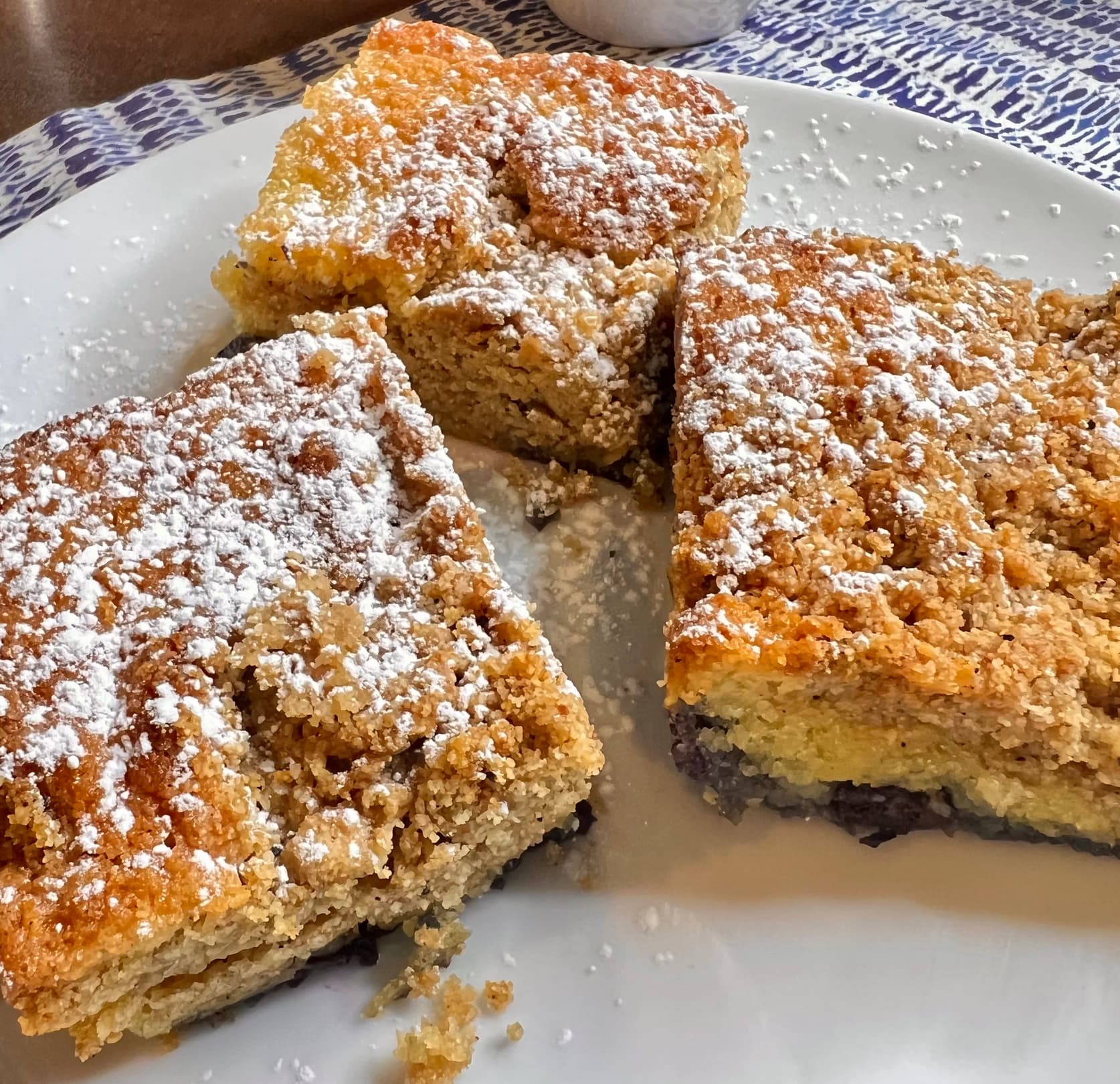 Plate full of almond blueberry coffee cake topped with powdered sugar