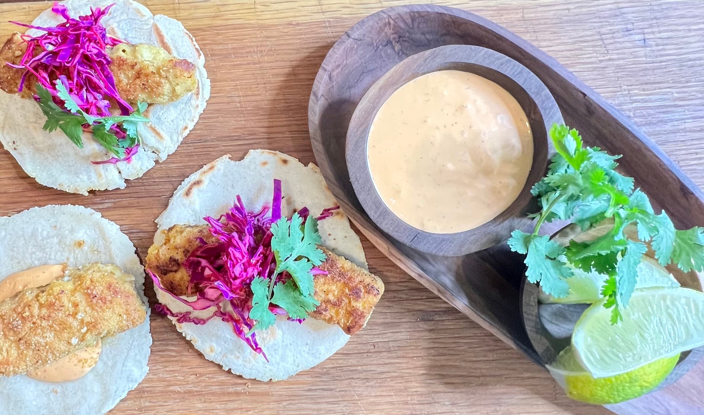 Platter full of fish tacos with dipping sauce