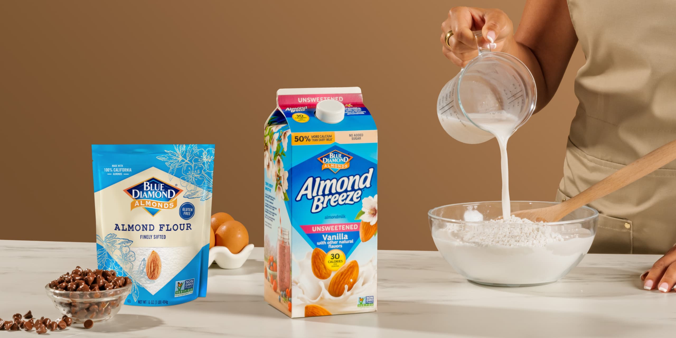 Woman pouring Almond Breeze almondmilk into a bowl of Blue Diamond almond flour.