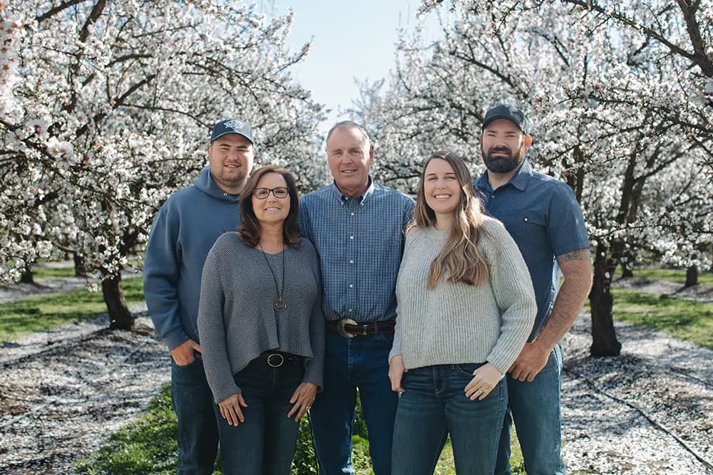 A Blue Diamond Grower Family standing in an almond orchard