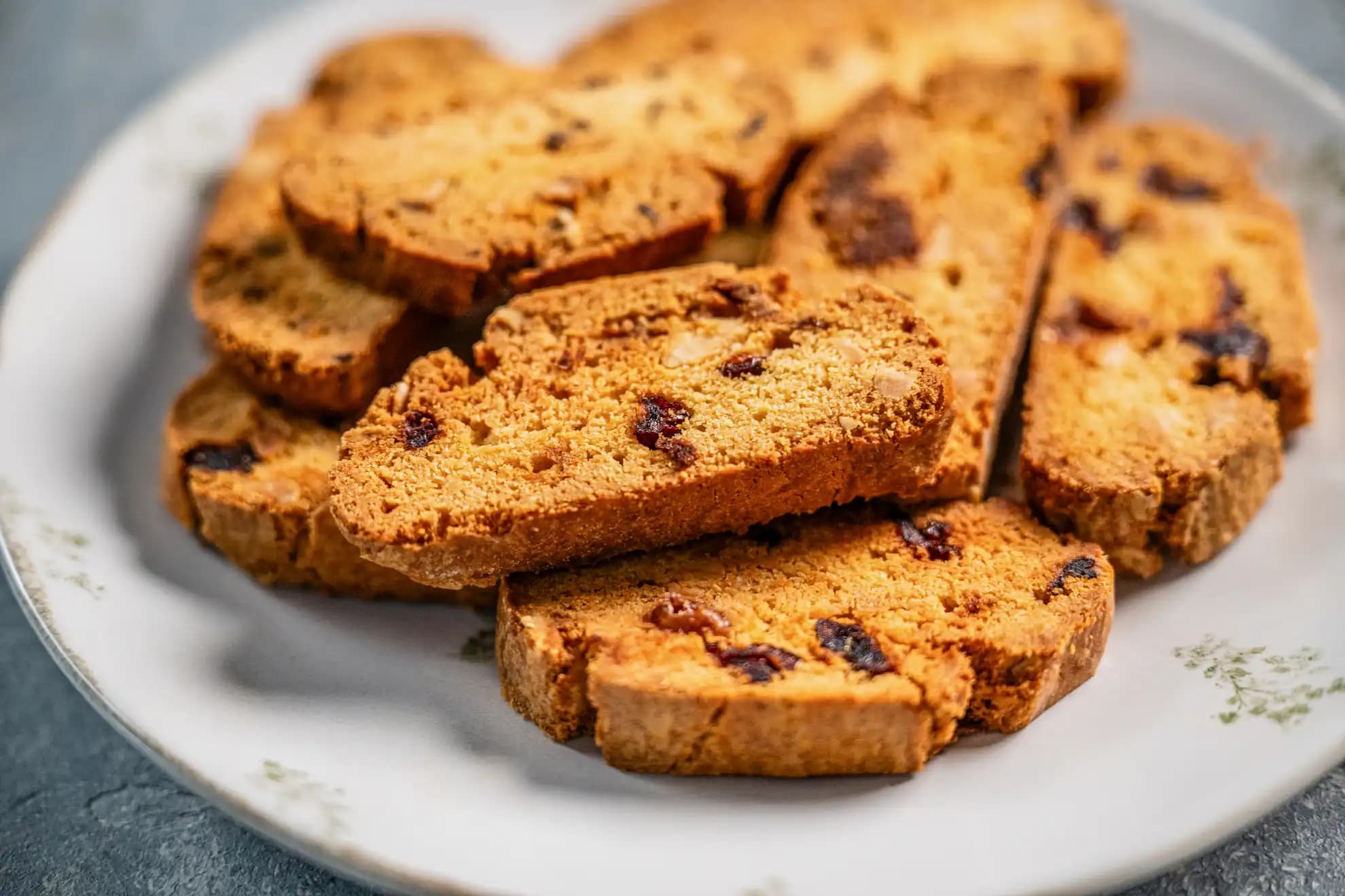 Plate of almond biscotti with dried cranberries and chopped almonds, stacked to showcase their crisp, toasted texture.