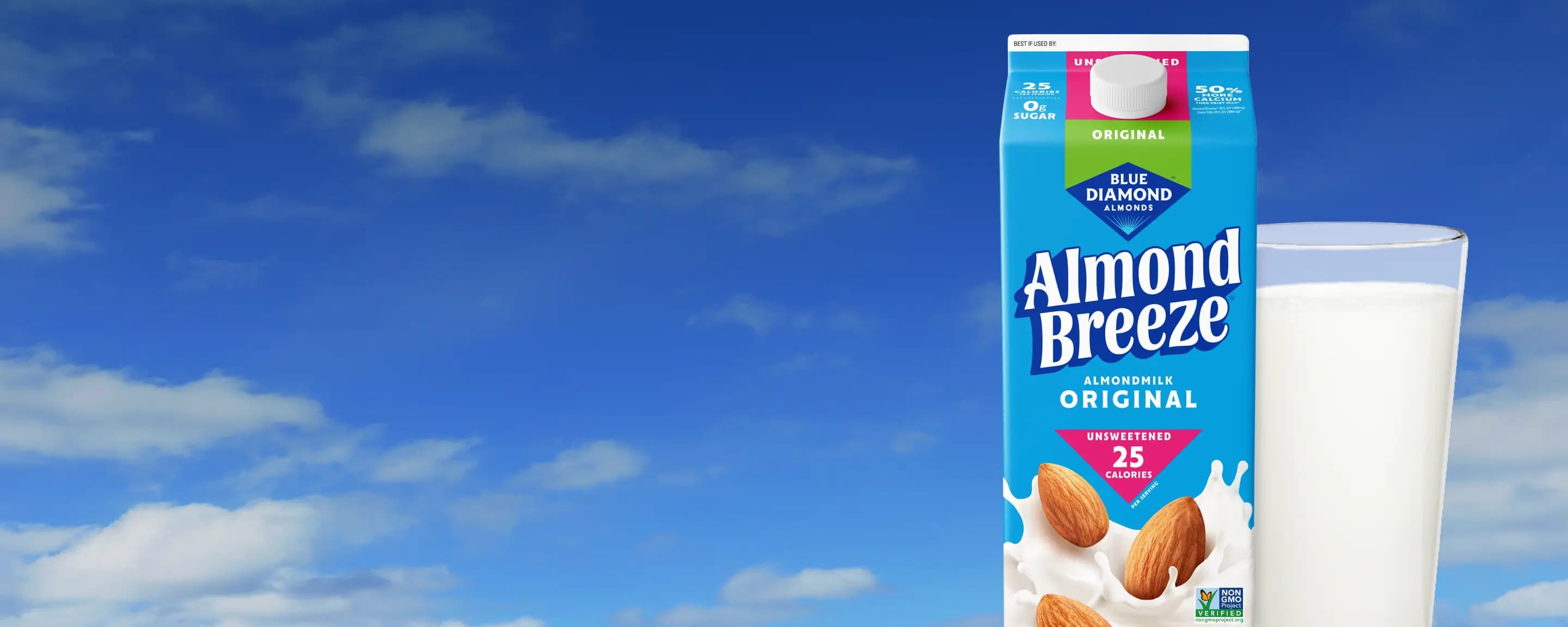Blue Diamond Almond Breeze Original Unsweetened Almondmilk carton beside a full glass of almondmilk against a bright blue sky with soft white clouds.